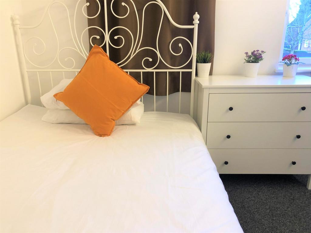 A cozy single bedroom featuring a decorative wh...