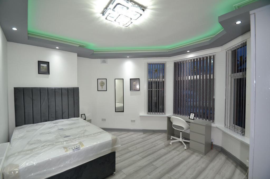 Bright, modern double bedroom with a tall uphol...