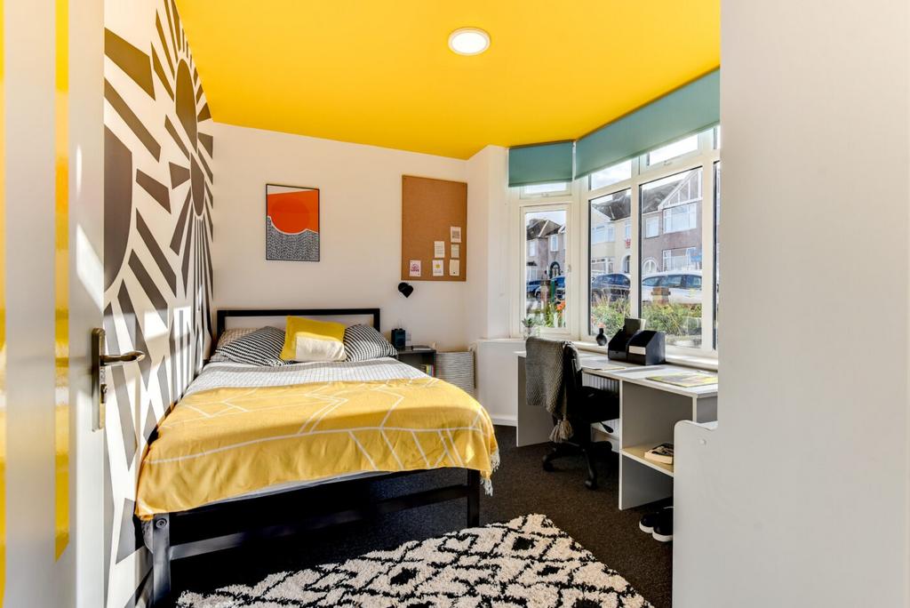 Bright, stylish bedroom with a bold yellow ceil...