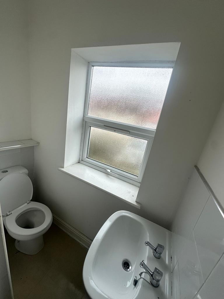 Compact white bathroom with a toilet and pedest...