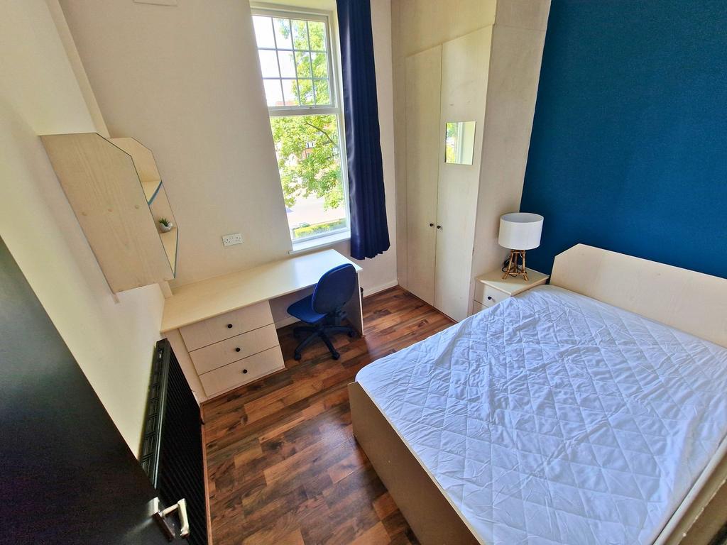Bright, well-furnished bedroom featuring a comf...