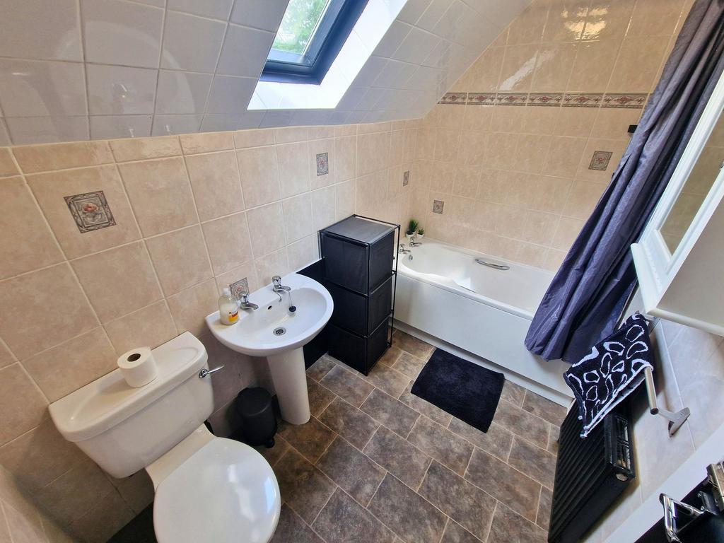 Bright, tiled bathroom with a bathtub under a s...