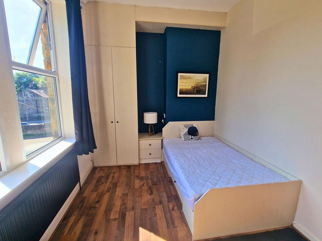 Bright single bedroom with a large window letti...