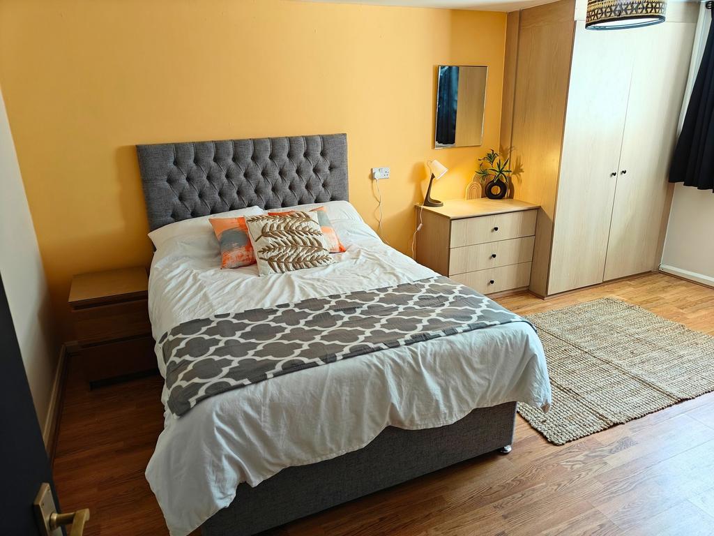 Bright, neatly furnished bedroom with a comfort...