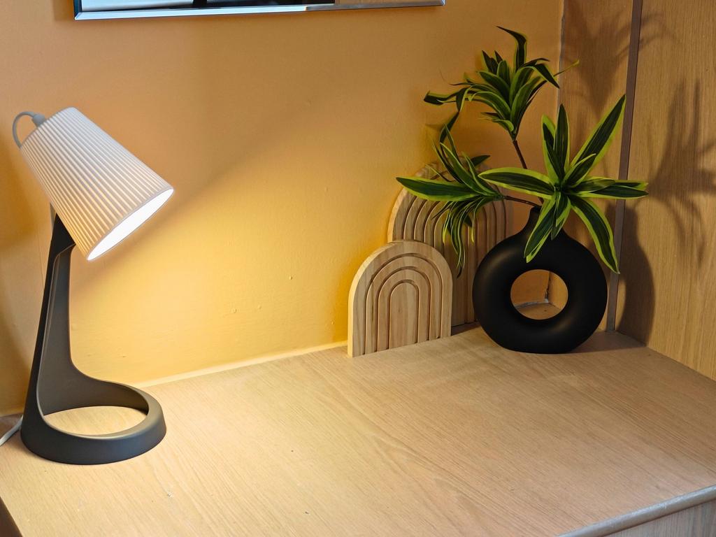 Well-lit desk corner with a modern table lamp, ...
