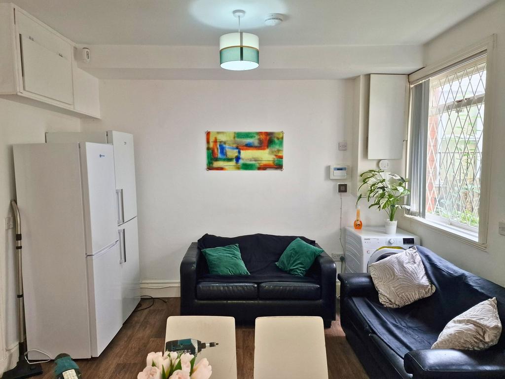 Bright, tidy lounge with two black leather sofa...
