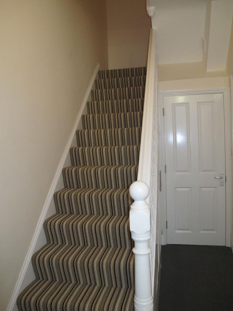 Carpeted staircase with a striped runner, white...
