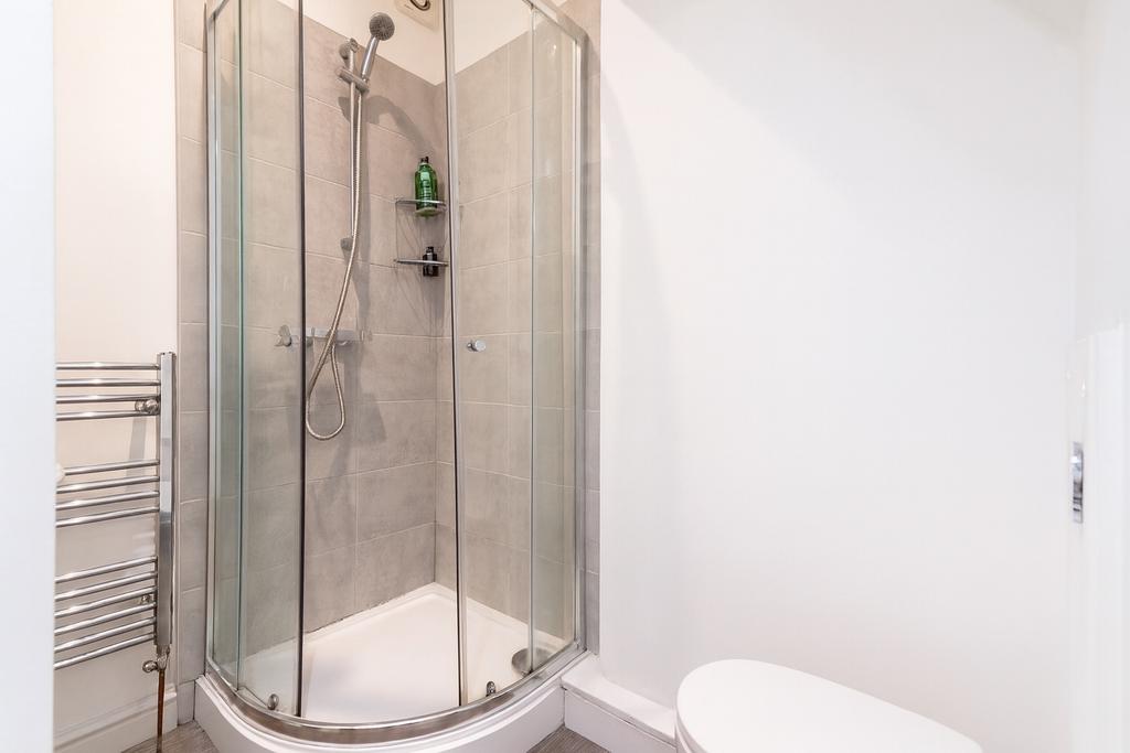 Bright, modern bathroom with a curved glass sho...