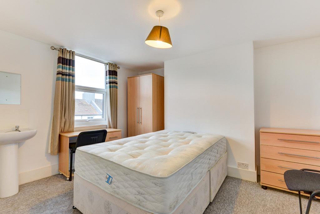 Bright, neutrally decorated bedroom with a comf...