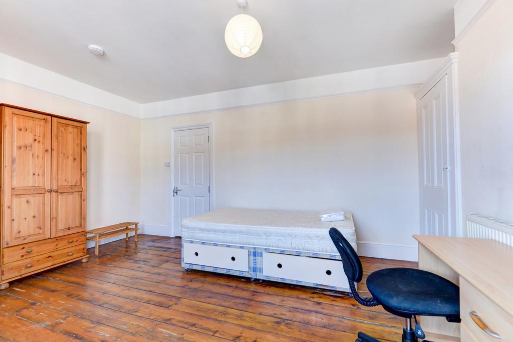 A bright and tidy bedroom featuring wooden floo...
