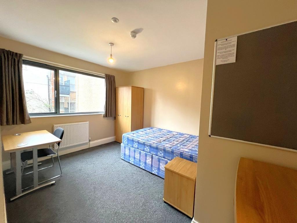 Bright, simply furnished bedroom with a large w...