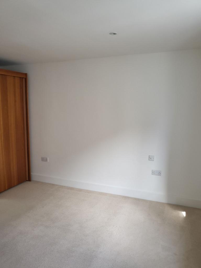 Bright, neutral bedroom with light carpet, buil...
