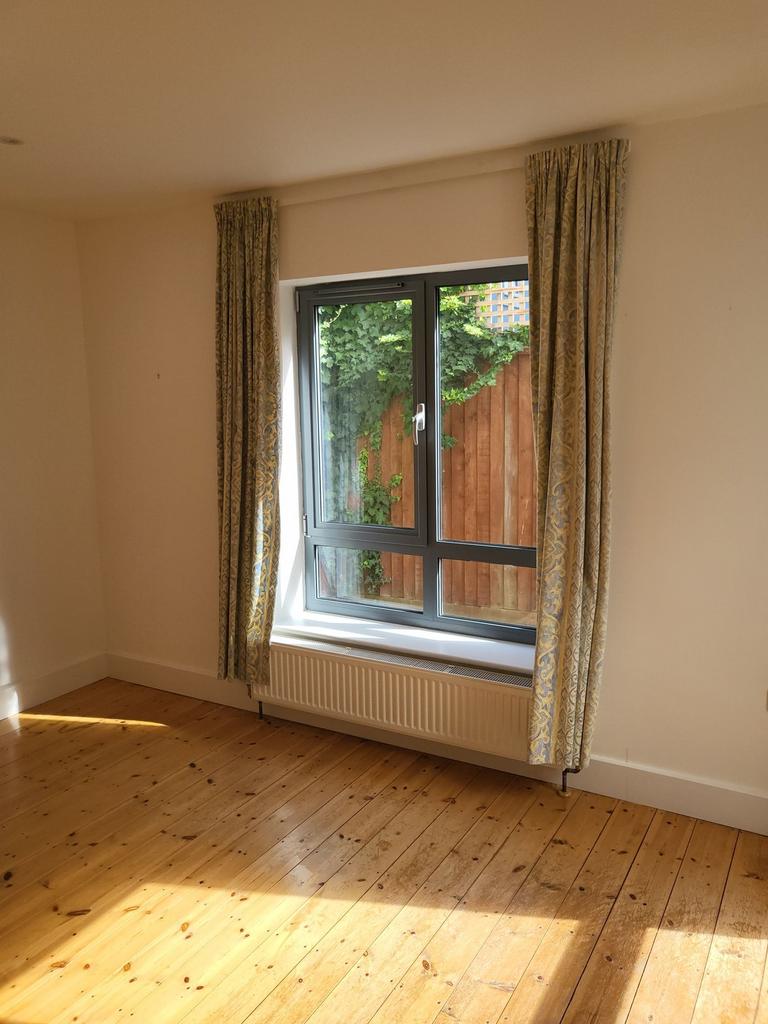 Bright bedroom with natural wood floors, a larg...