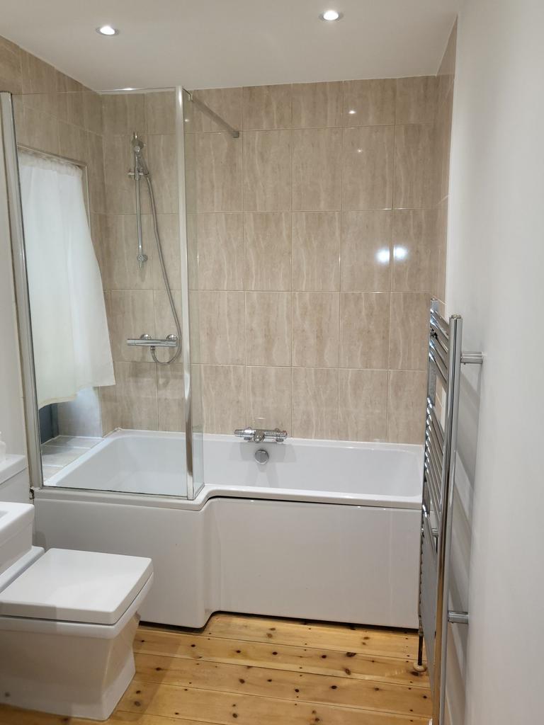 Bright, modern bathroom with an L-shaped bath a...