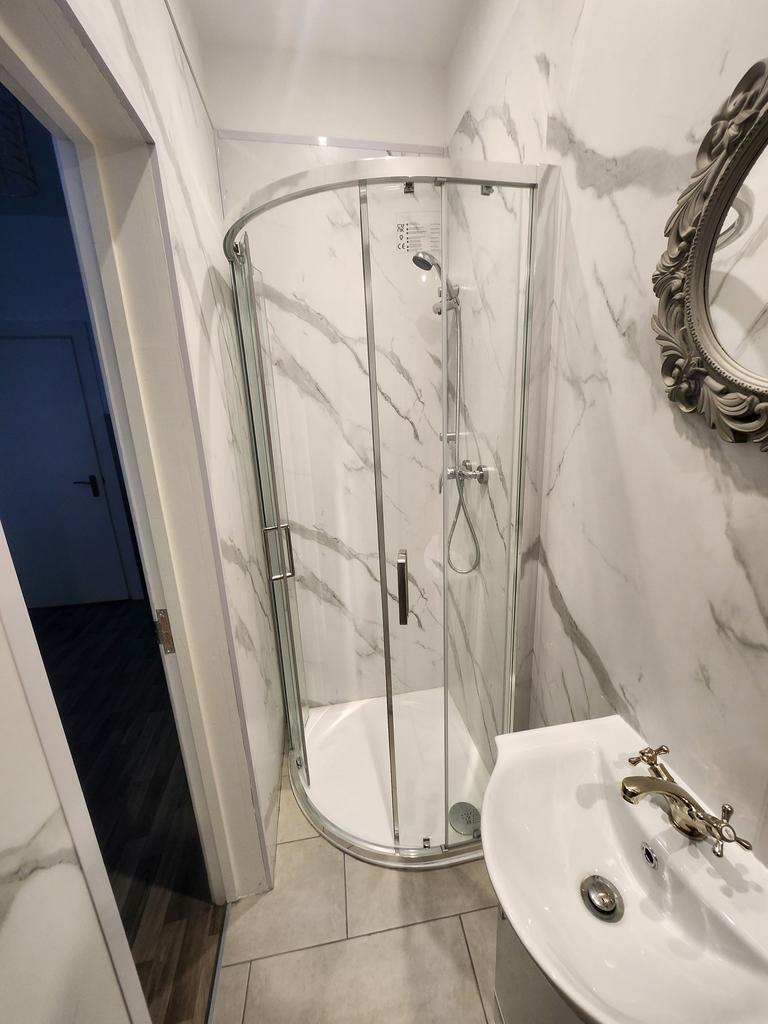 Bright modern bathroom with a corner glass show...