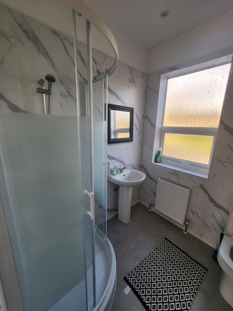 Bright, modern bathroom with a curved glass sho...