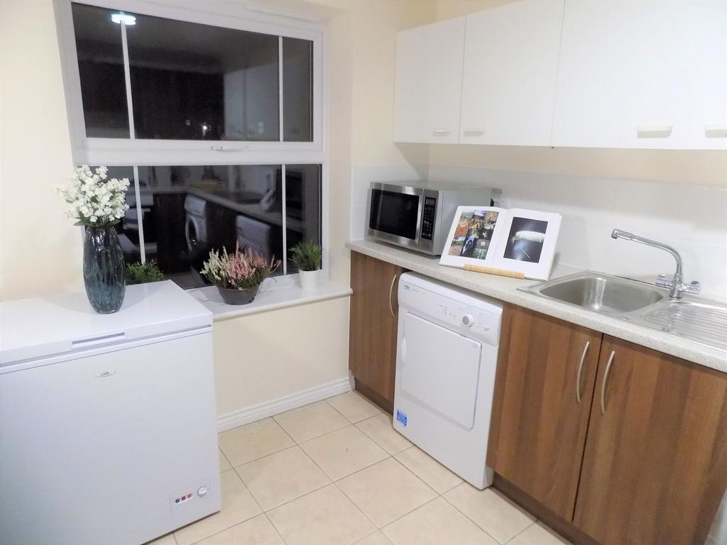 Bright, tidy kitchen with neutral tiles, wood-e...