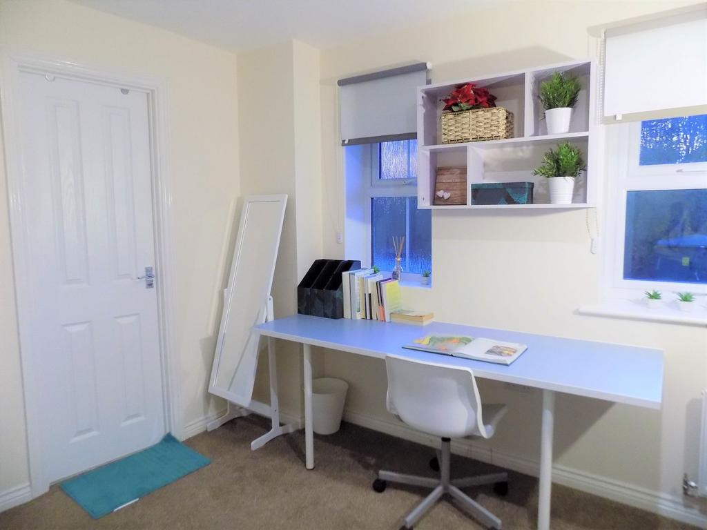 Bright, tidy study area with a long desk, ergon...