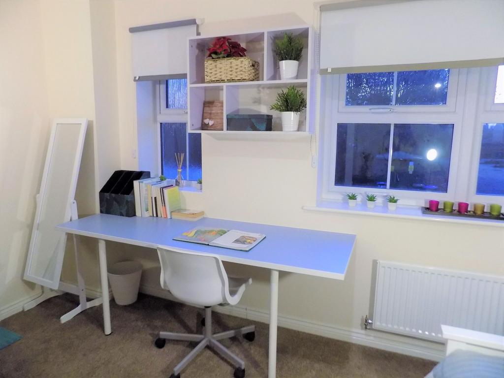 Bright, tidy study area with a long desk, ergon...