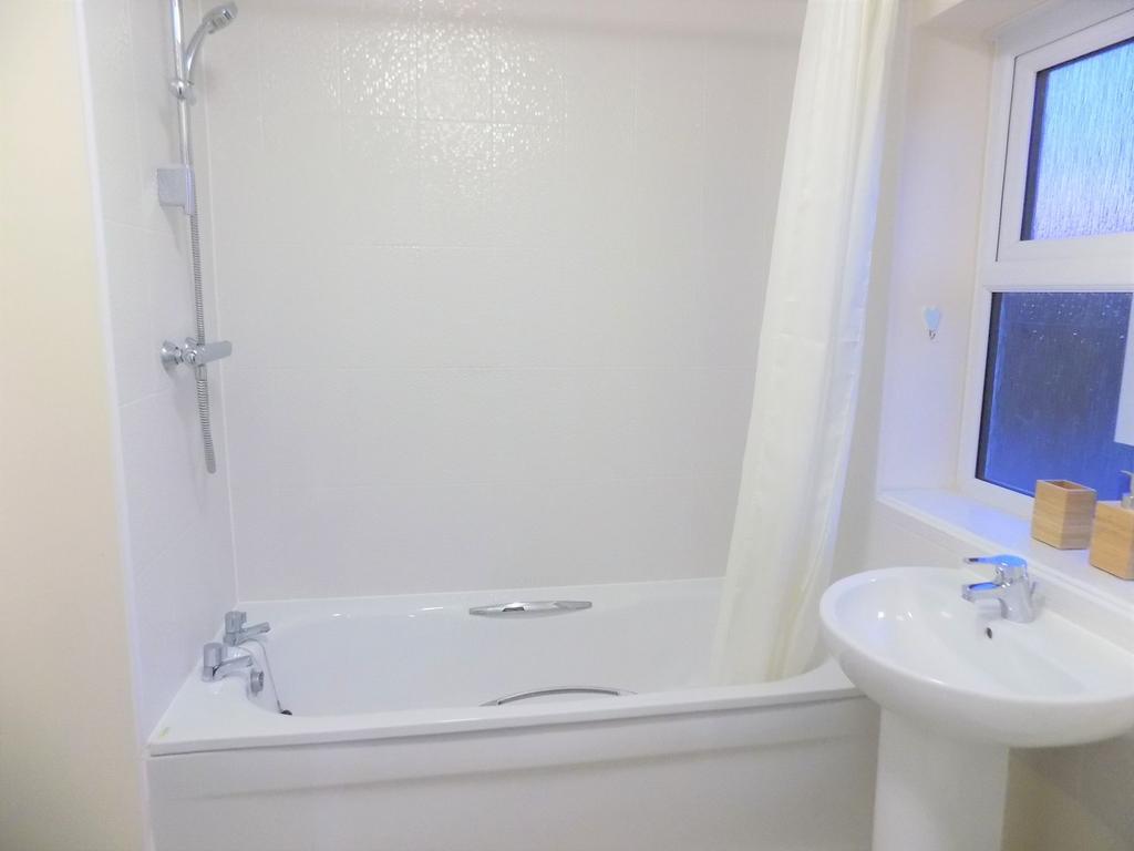 Bright, modern bathroom with a white bathtub an...
