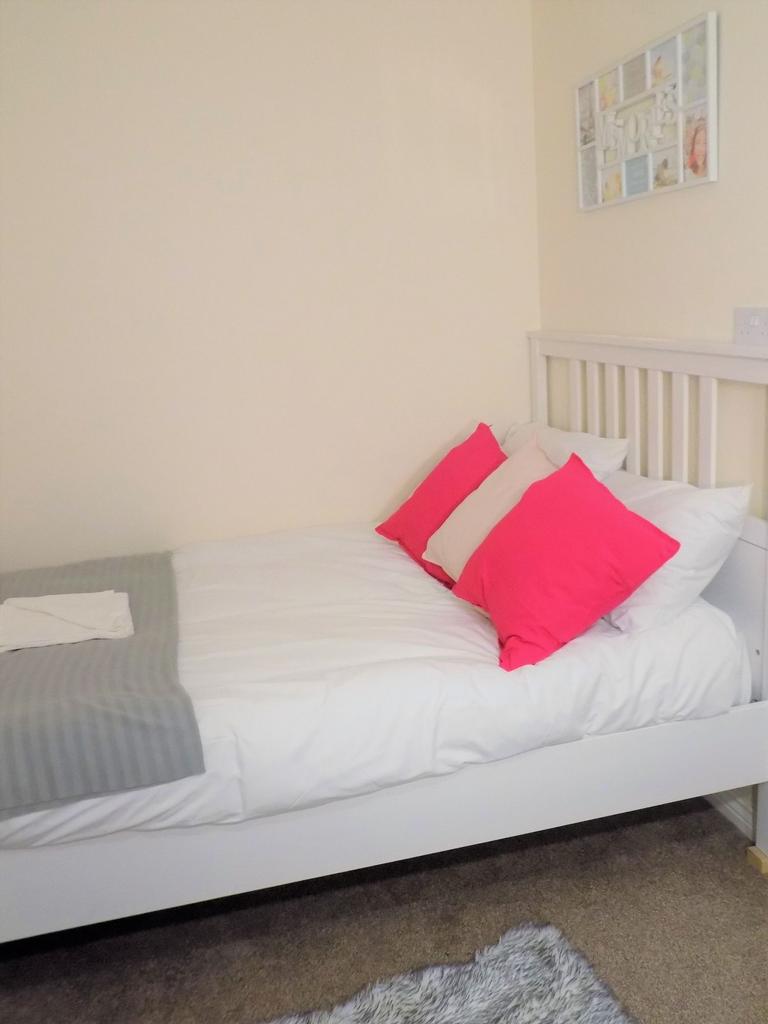 Bright, neatly made bedroom with white wood bed...