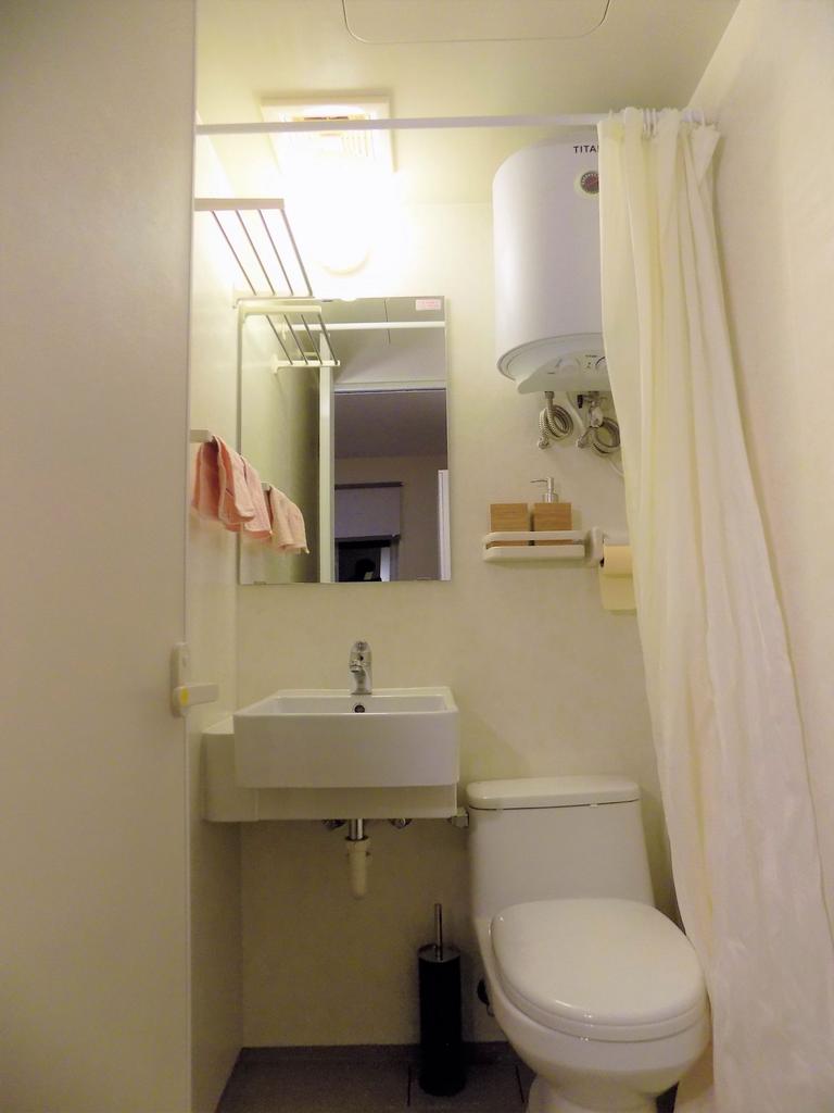 Neat compact bathroom with a wall-mounted sink,...