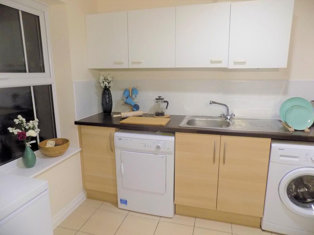 Neat modern kitchen with light wood cabinets, d...