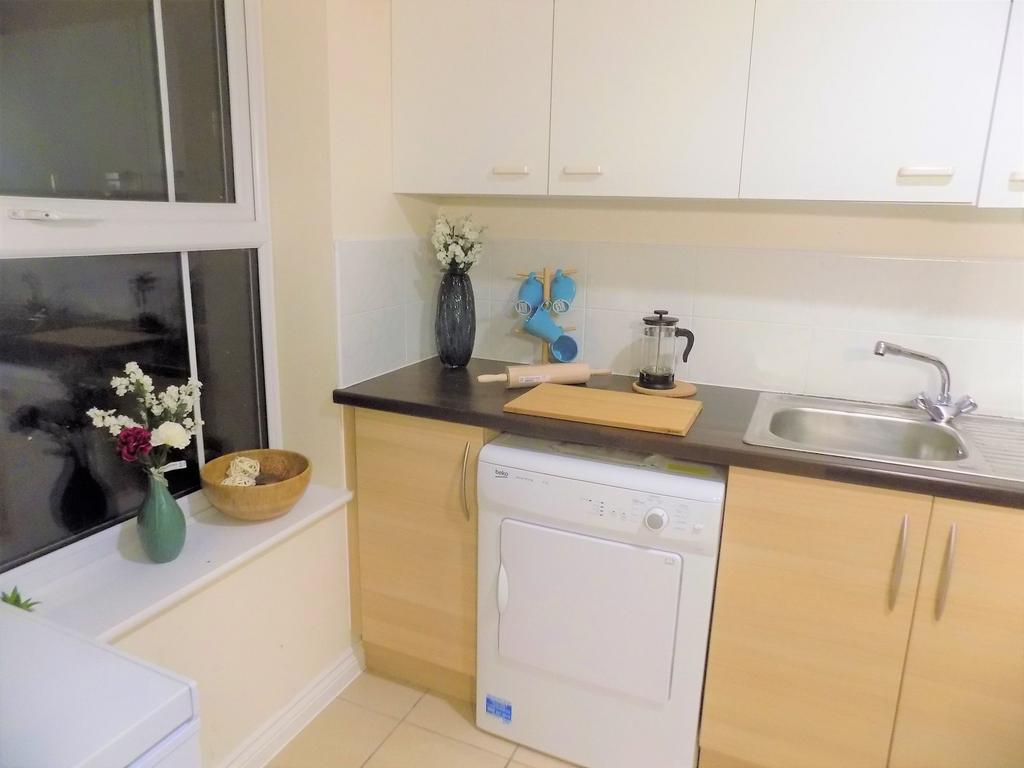 Bright, tidy kitchen with light-wood cabinets, ...