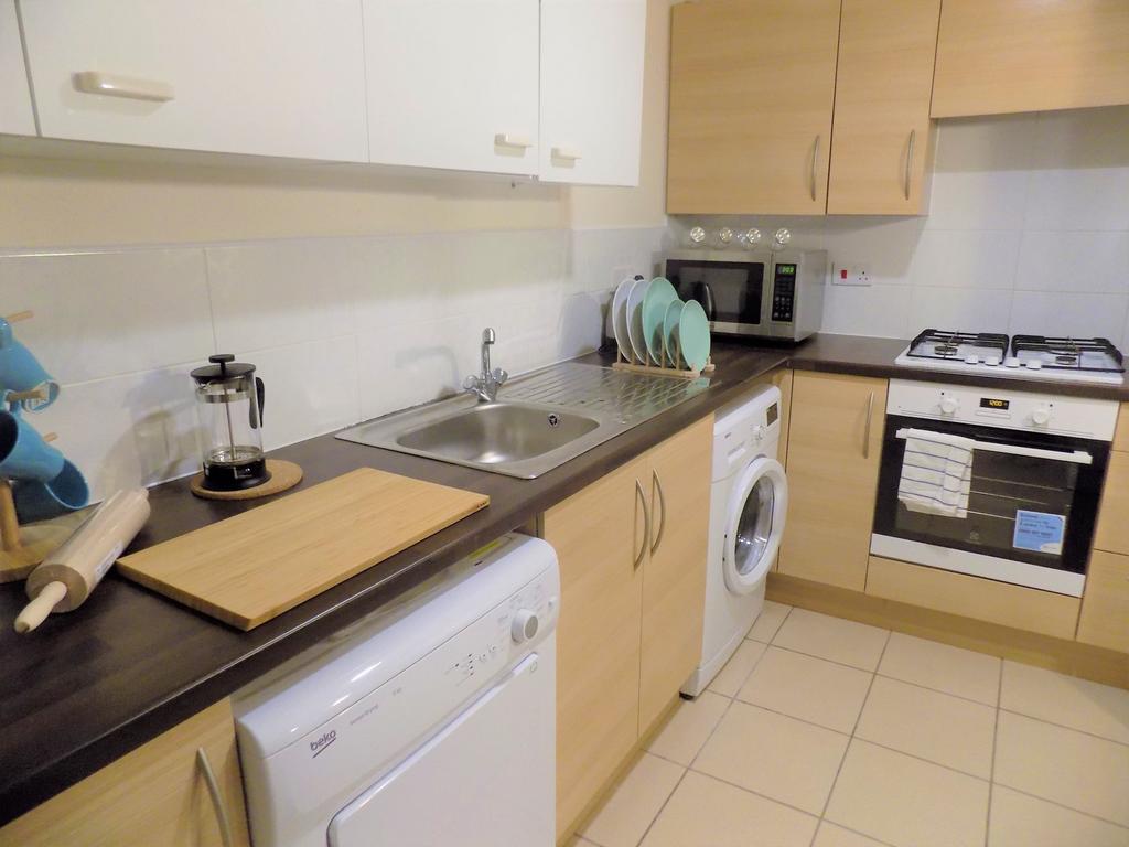 Bright, modern fitted kitchen with light wood c...