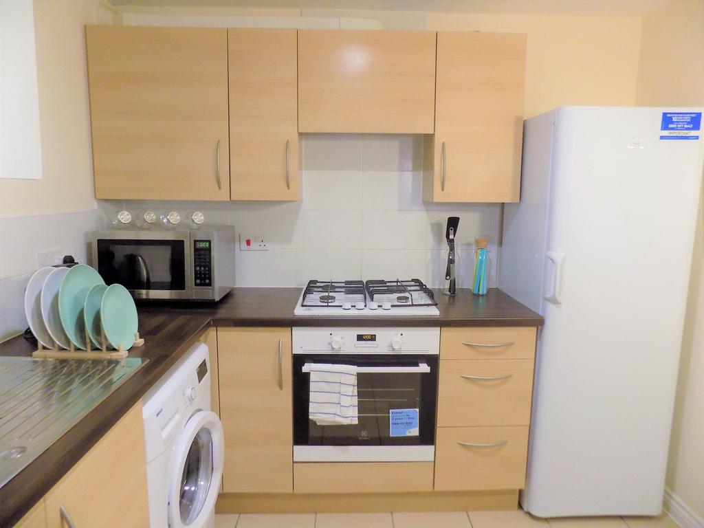Well-equipped modern kitchen with light wood ca...