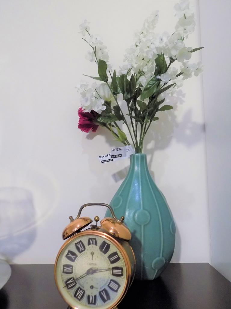 Stylish vignette with a teal ceramic vase of wh...