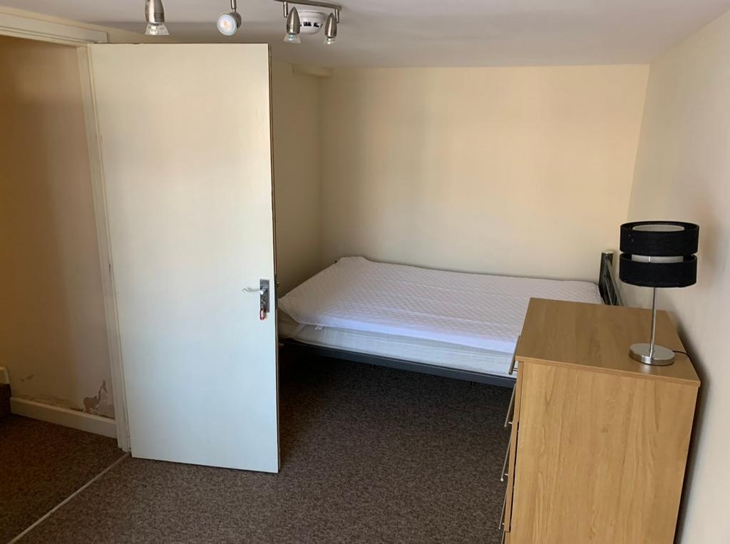 A tidy single bedroom featuring a bed and a dre...