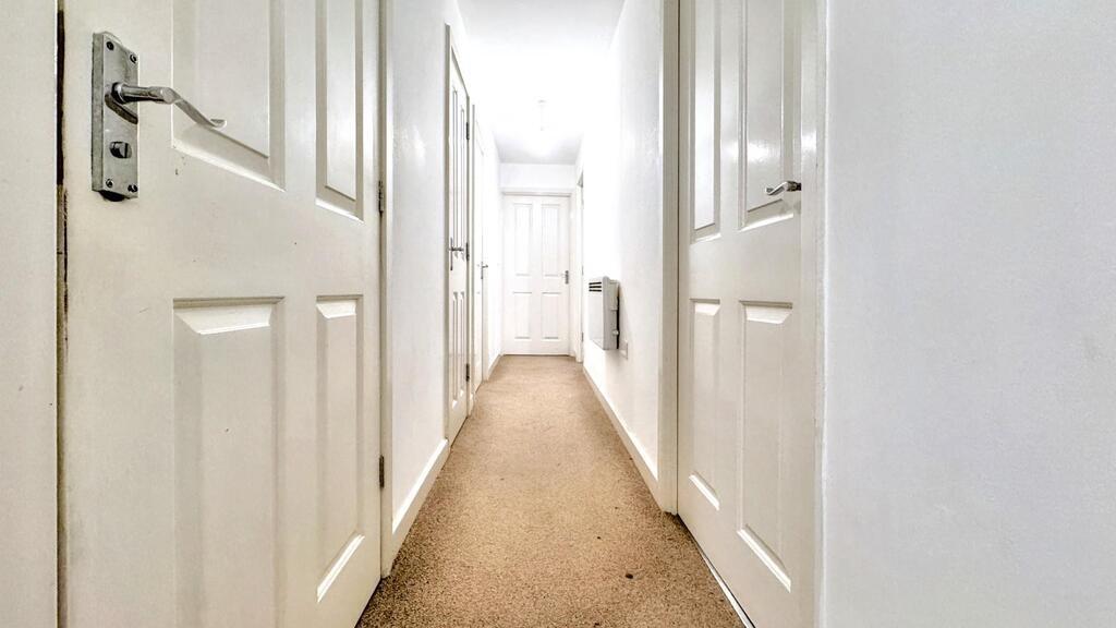 Bright, clean internal hallway with multiple do...