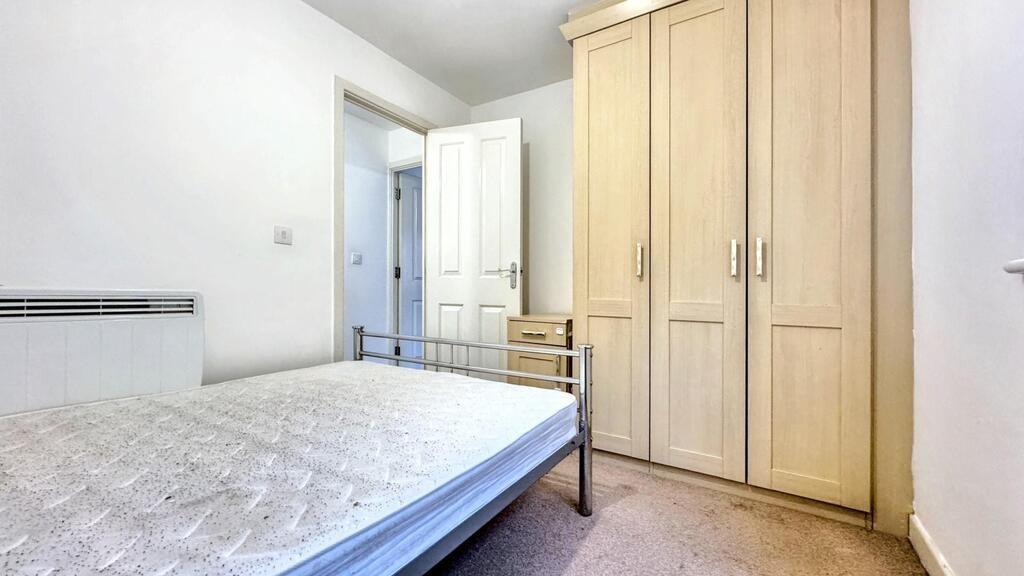 Bright, simply furnished bedroom with a double ...