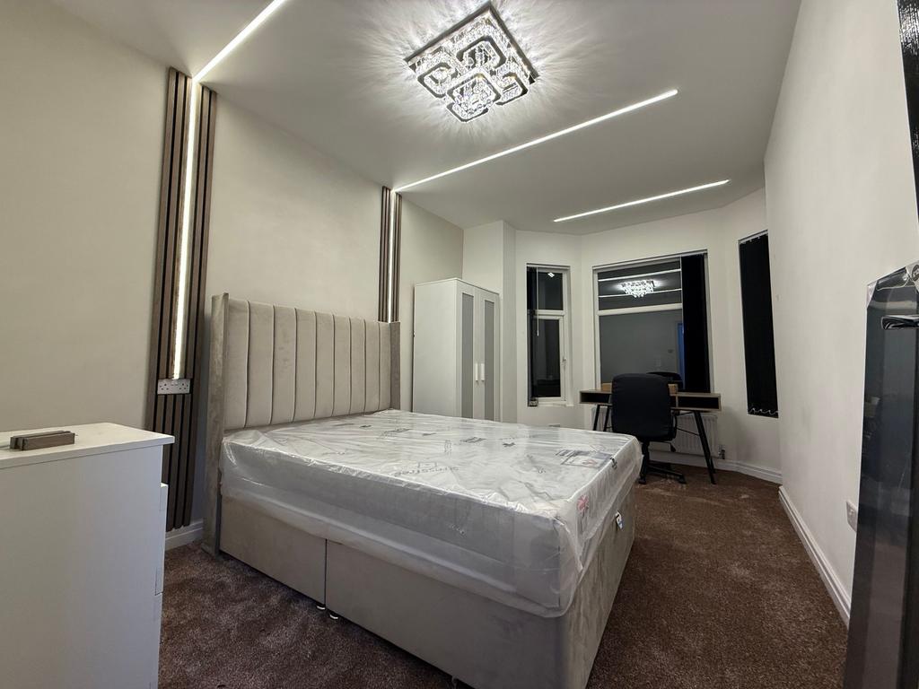 Bright, modern double bedroom with a tall uphol...