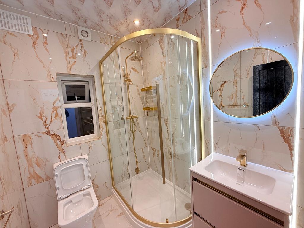 Modern, fully tiled bathroom with a curved glas...