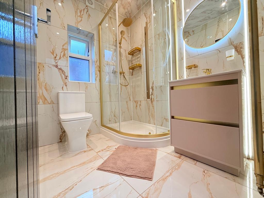 Stylish marble-tiled bathroom with a curved gla...
