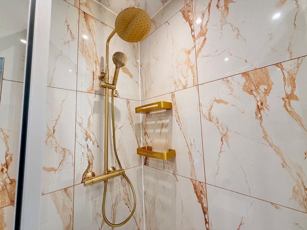 Bright, modern bathroom shower with marble-effe...