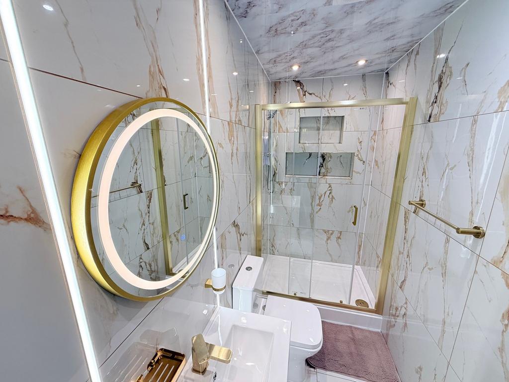 Stylish marble-tiled bathroom with a glass-encl...