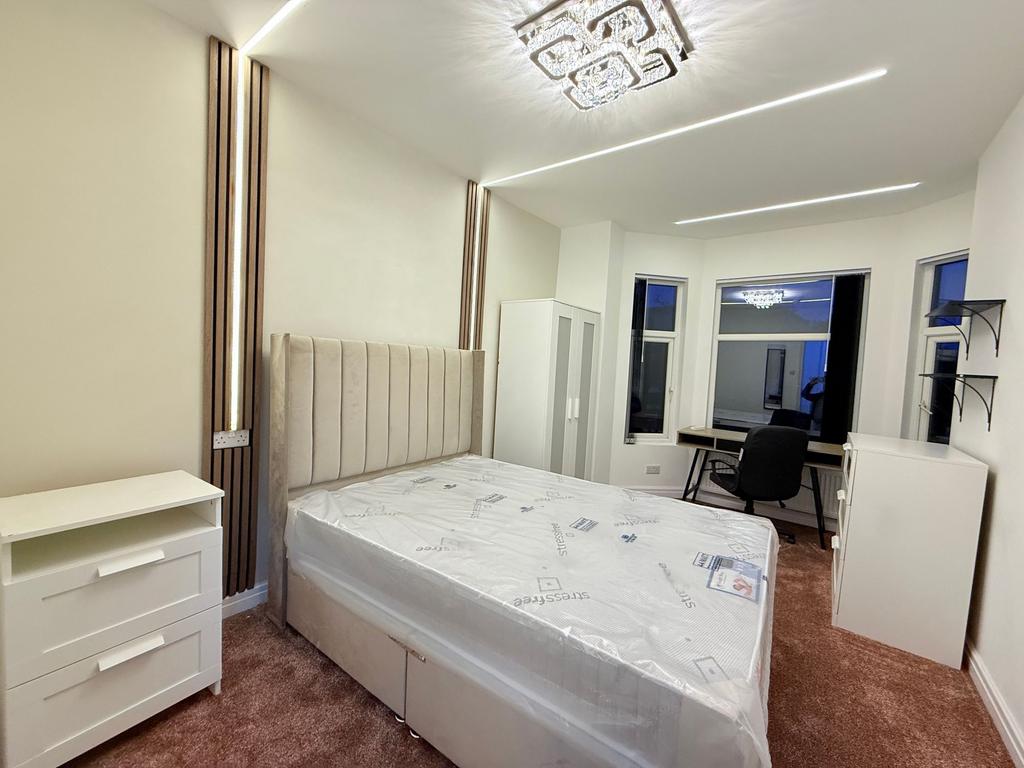 Bright, modern double bedroom with a tall uphol...