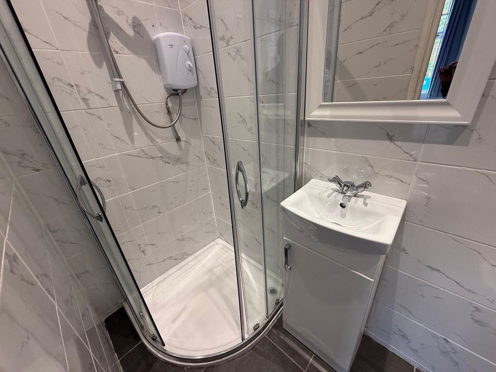 Bright, modern bathroom with a corner glass sho...