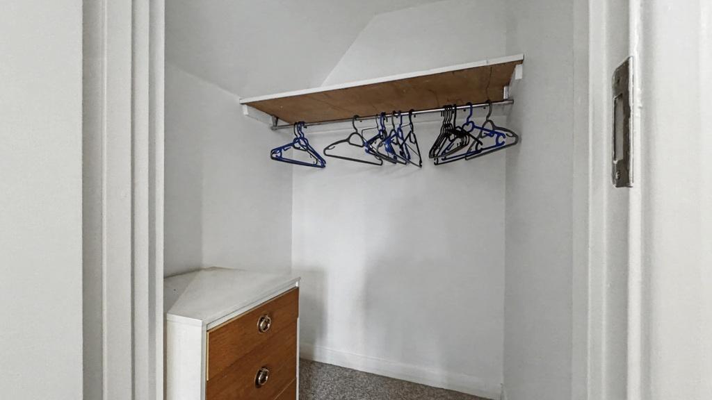 Small, clean storage/wardrobe space with a wood...