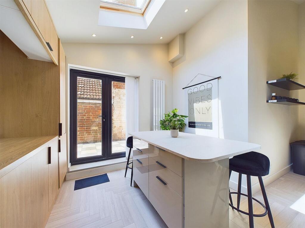 Bright modern kitchen with central island seati...