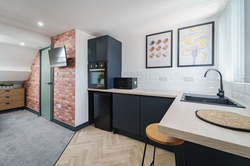 Modern kitchenette with matte dark cabinets, in...