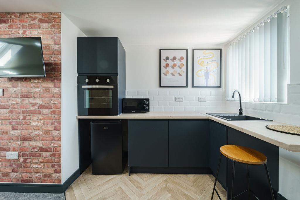 Modern fitted kitchen with dark cabinetry, inte...