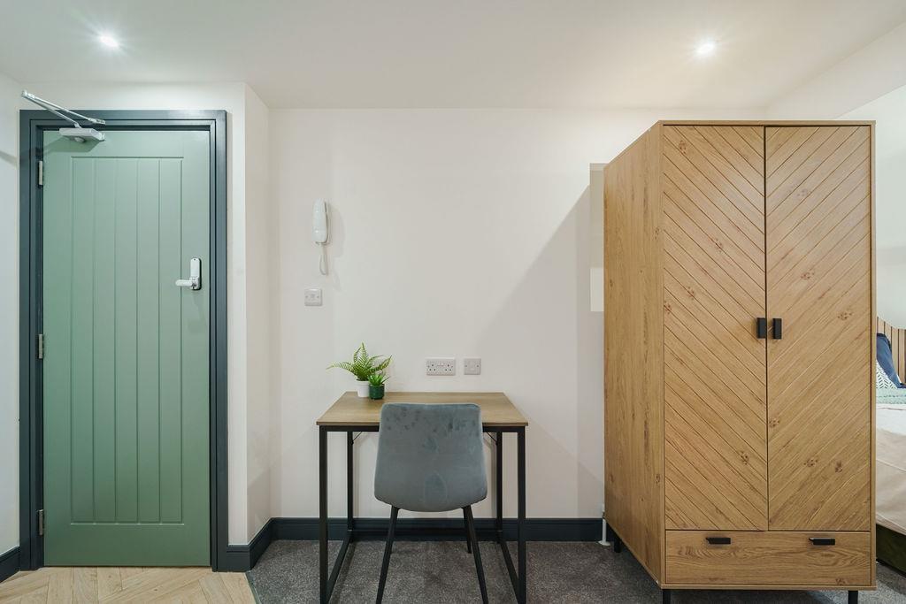 Bright, tidy bedroom corner with a neat study d...