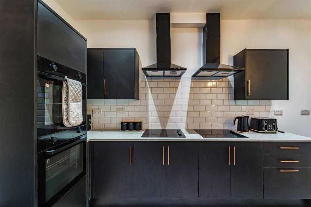 Modern fitted kitchen with dark cabinetry, buil...