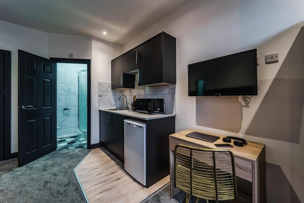 Modern kitchenette with dark cabinetry, integra...