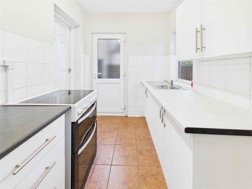 Bright, modern galley kitchen with white cabine...