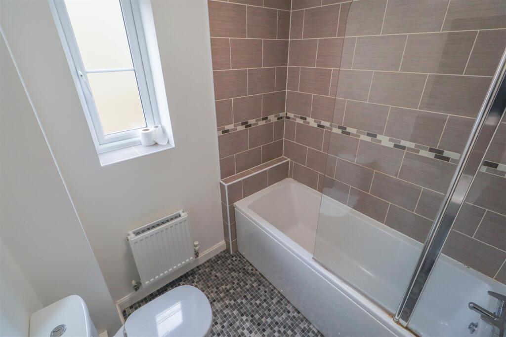 Modern bathroom with tiled bath and glass showe...